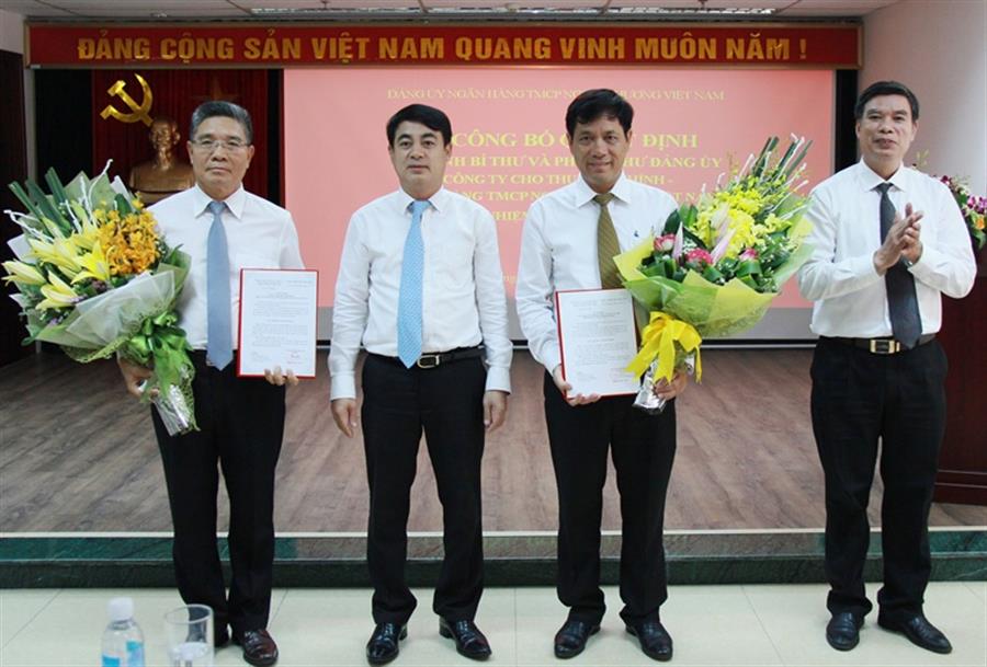 Bí thư Đảng ủy, Chủ tịch HĐQT Vietcombank Nghiêm Xuân Thành (thứ 2 từ trái sang) và Phó Bí thư thường trực Đảng ủy Vũ Tiến Duật (ngoài cùng bên phải) trao quyết định và tặng hoa chúc mừng tân Bí thư và Phó Bí thư Đảng ủy Công ty VCBL